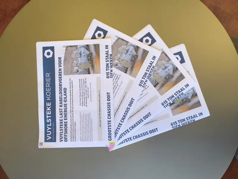 Meerdere exemplaren van een professioneel vormgegeven bedrijfskrant liggen op een tafel, klaar voor verspreiding aan klanten, medewerkers en partners.