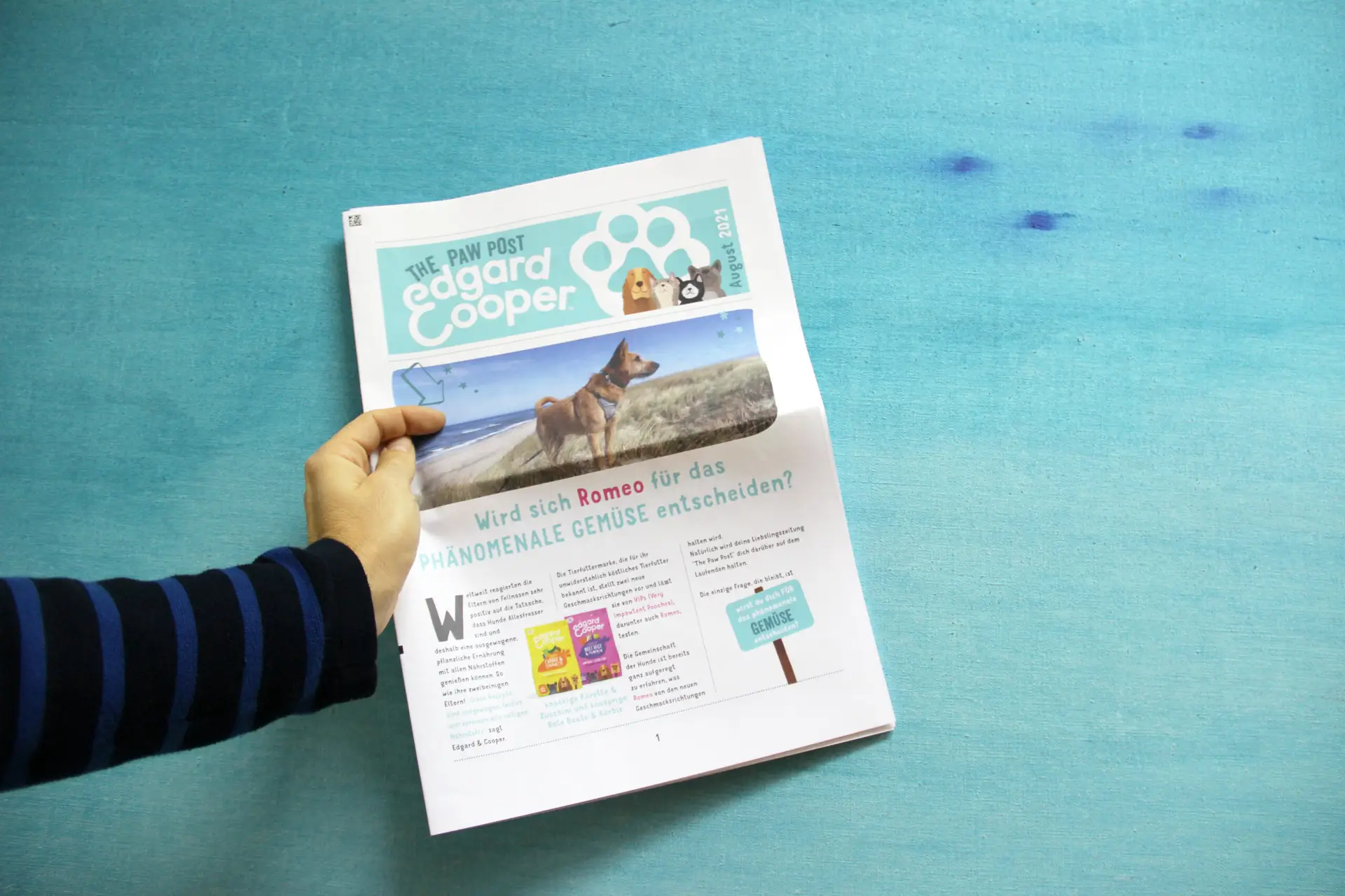 Persoon houdt een gepersonaliseerde krant vast met een voorpagina over een hond en informatieve artikels voor huisdiereigenaars.