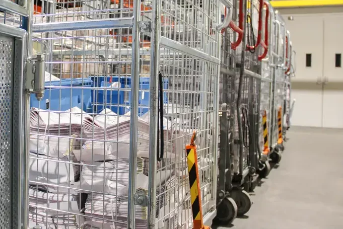 Gedrukte kranten worden na productie verzameld in rolcontainers voor een efficiënte verwerking en verzending naar de eindontvanger.