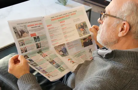 Lid van een vereniging bekijkt een gepersonaliseerde krant met een activiteitenkalender, nieuwsberichten en foto's van lokale evenementen.