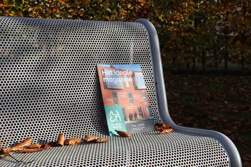 Gepersonaliseerd magazine van Genscom ligt op een bankje in een groene omgeving en illustreert de blijvende impact van hoogwaardige printcommunicatie.