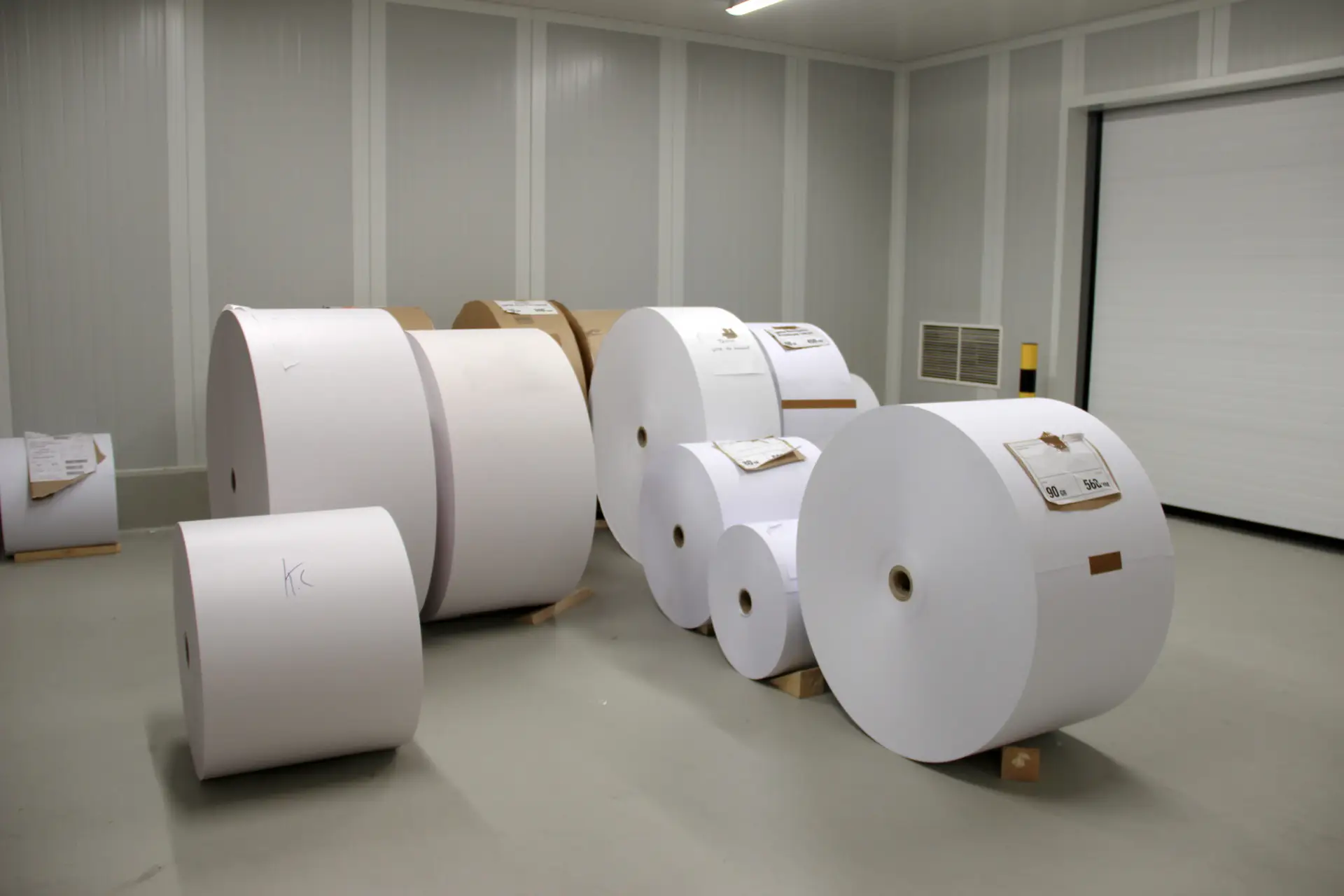 Papierrollen van verschillende formaten en papiersoorten voor de productie van kranten en magazines bij Genscom.